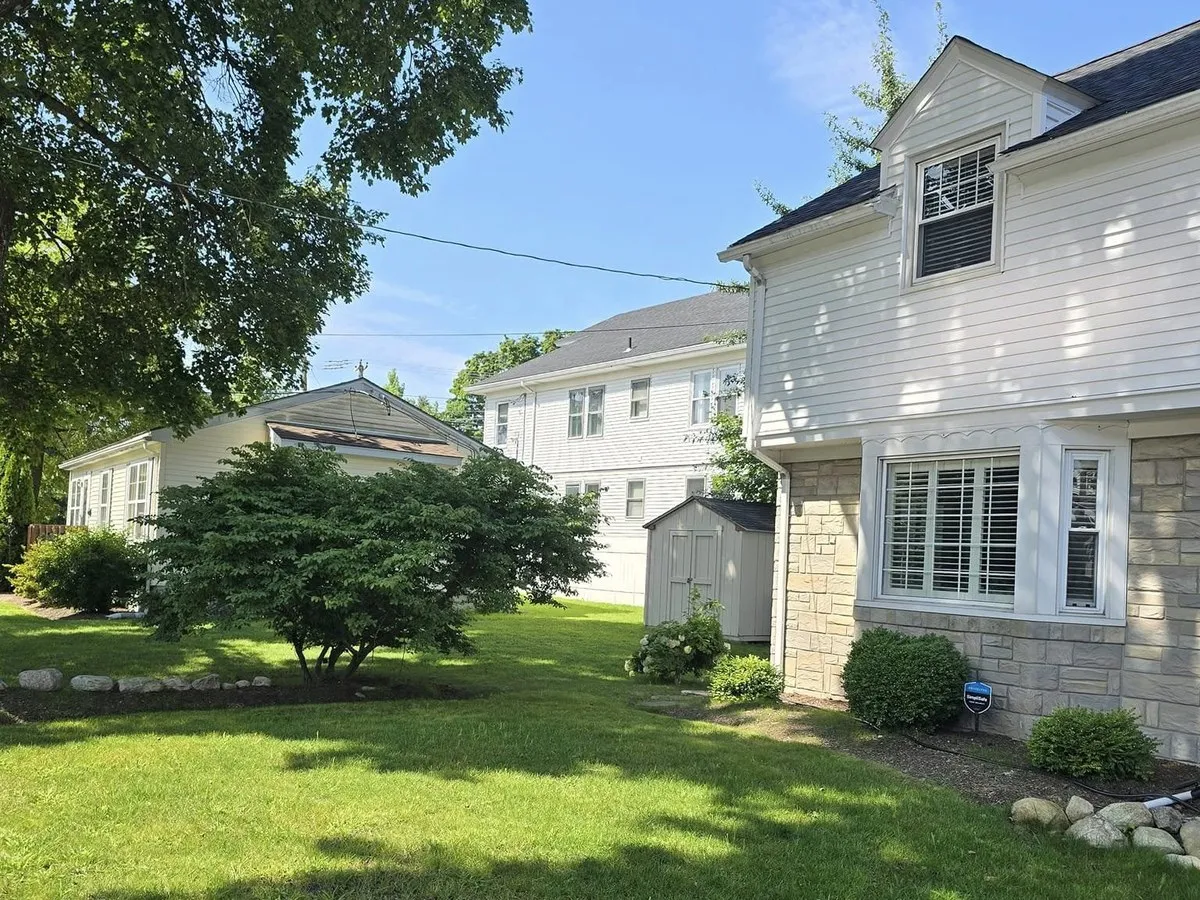 Freshly maintained green lawn with shrub beds between two houses